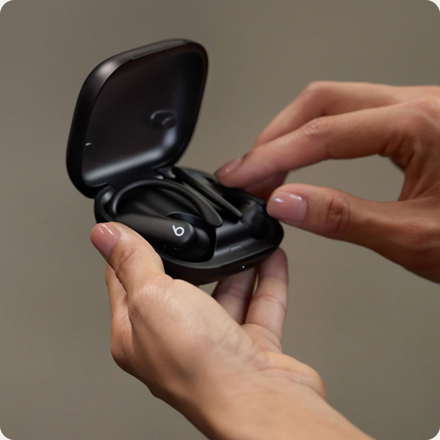 特寫:一個人拿著打開的充電盒,裡面放著 Powerbeats Pro 2 耳機