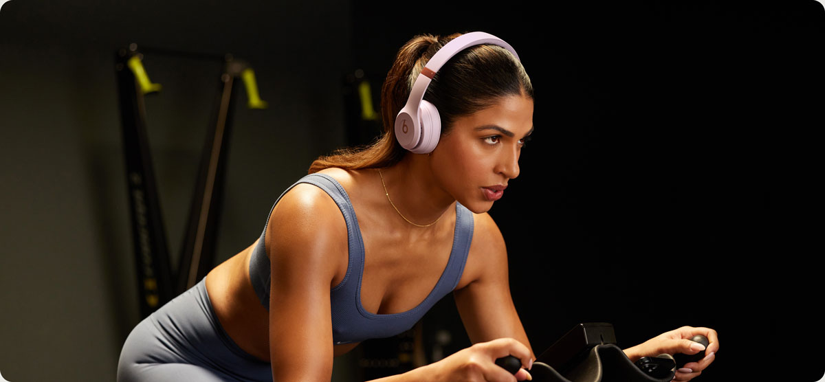 Woman on an exercise bike wearing Beats Solo 4 headphones